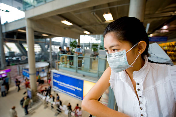 Woman wearing a face mask at the airport young woman with face mask at the international airport in bangkok bkk stock pictures, royalty-free photos & images