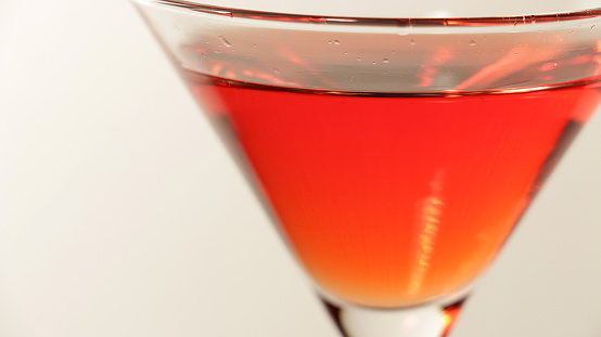 Close up shot of a red martini drink in an elegant cocktail glass.