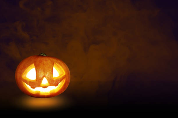 istock Pumpkin Jack O Lantern on a stone and under a tree with the sky is creepy background 1182654008