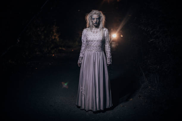 istock Scary witch standing on the road at night 1182654848