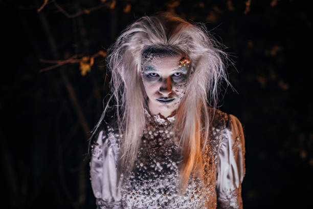 istock Scary witch in white dress standing in the dark 1182655145