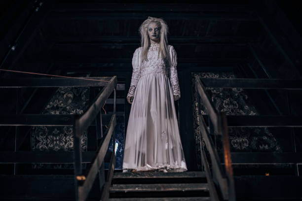 One woman, she masked herself in a scary witch for halloween, standing in front of abandoned house.