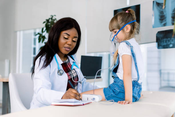 young african female doctor helping to little girl with nebulizer mask. medical doctor applying medicine inhalation treatment on a little girl with asthma inhalation therapy by the mask of inhaler. - respiratory system imagens e fotografias de stock