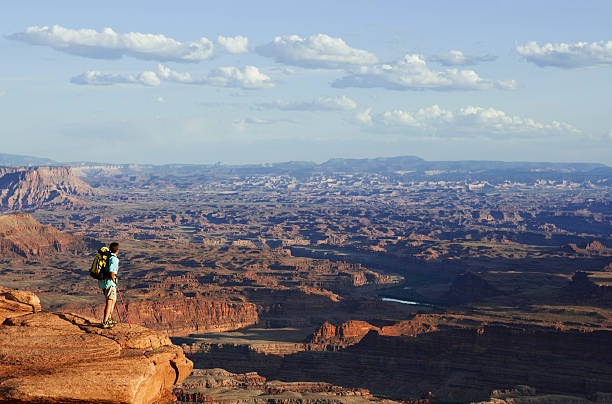 istock Man Wearing Backpack Standing On Rocky Ledge Looking At View 118265729