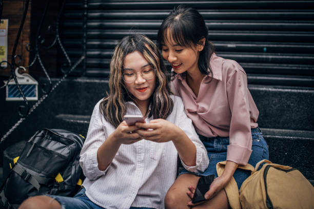 istock Young women sitting on steps and using smart phone 1182658986