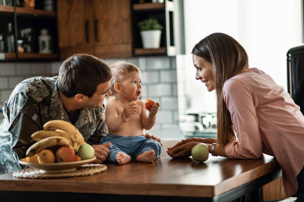 Happy military family enjoying together at home. Happy military officer and his wife spending time with their baby son who is eating fruit at home. national guard stock pictures, royalty-free photos & images