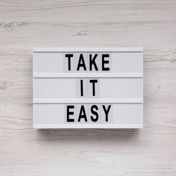istock 'Take it easy' words on a lightbox on a white wooden background, top view. Overhead, from above, flat lay. 1182659565