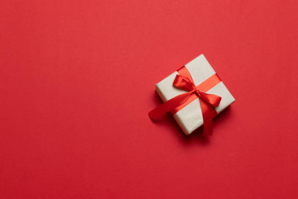istock Gift or present box with red ribbon bow on red table top view. Trendy composition for birthday, mother day or wedding. 1182659576