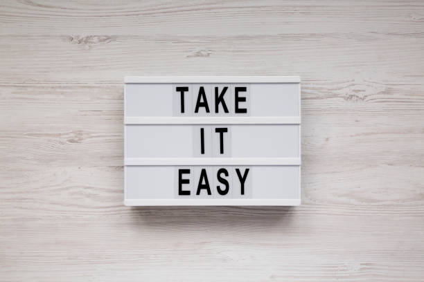istock 'Take it easy' words on a modern board on a white wooden background, top view. Overhead, from above, flat lay. 1182659591