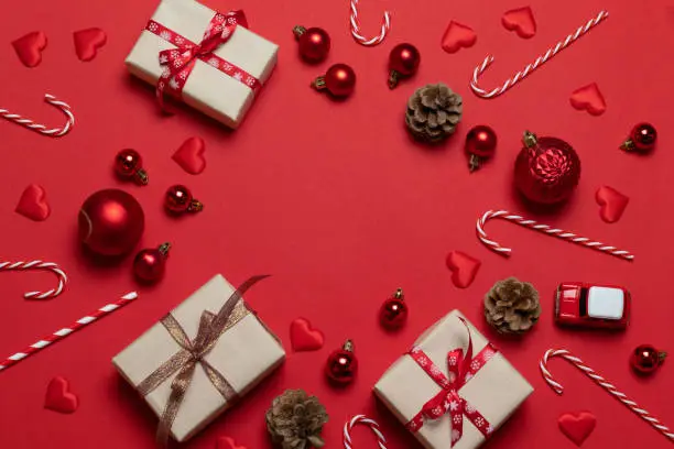 Photo of Christmas and New Year holiday banner with craft gift,car and fir cones on a red background. Flat lay, top view