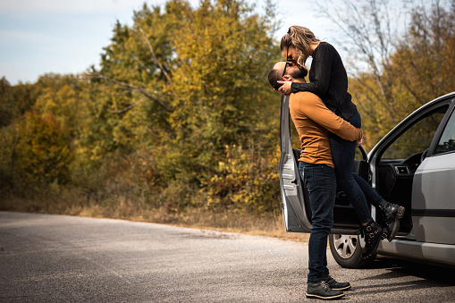 Young loving couple are kissing on the autumn road