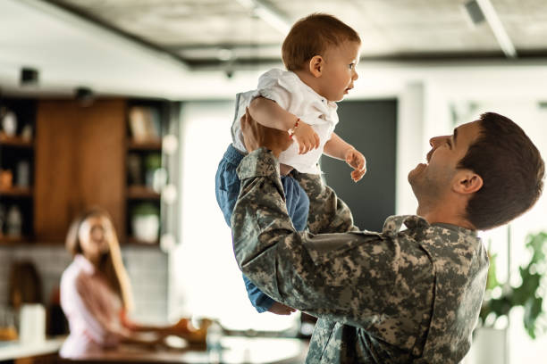 oficial militar feliz que tem o divertimento com seu filho do bebê em casa. - marine life - fotografias e filmes do acervo