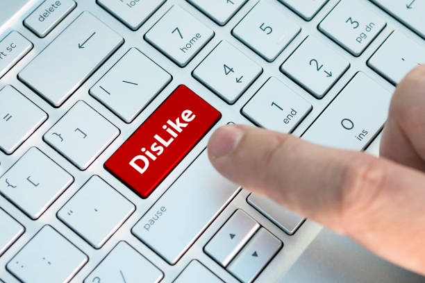 istock A dislike on keyboard button. A male finger presses a color button on a gray silver keyboard of a modern laptop. Button with inscription close up.s. 1182660778