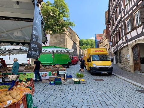 Schwäbisch Hall, Germany - September, 11 - 2019: View of the town square with medieval buildings, market stands and people. DHL parcel service car visible.