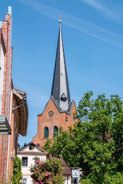 istock A historic red brick steeple tower behind houses and trees. 1182662741