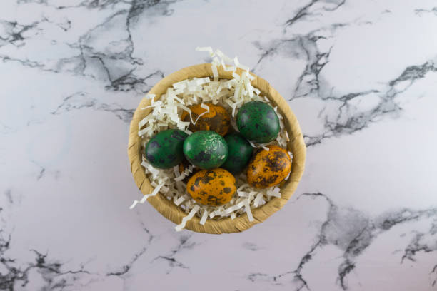 Marble Easter flat lay background with painted quail Easter eggs in a wicker basket.