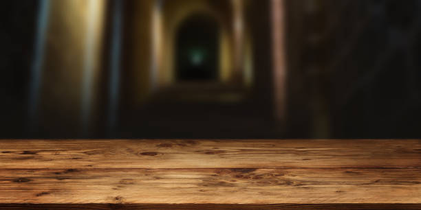 Empty wood table surface in front of gloomy vault with short depth of field for a halloween background