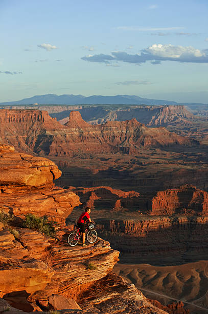 Mountain Biker On Edge Of Rocky Ledge In Moab, Utah Young male riding mountain bike stopped to look at magnificent view in Canyonlands National Park. slickrock trail stock pictures, royalty-free photos & images