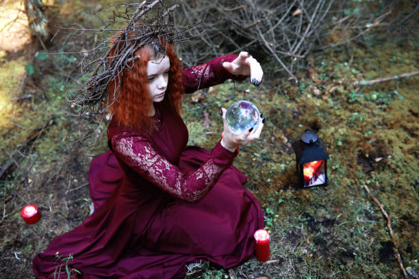 istock The red-haired witch holds a ritual with a crystal ball 1182664442