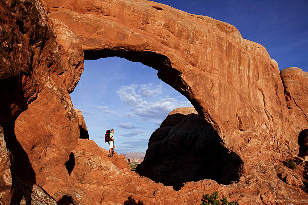 istock Hiker Standing Under Huge Arch In Arches National Park 118266639
