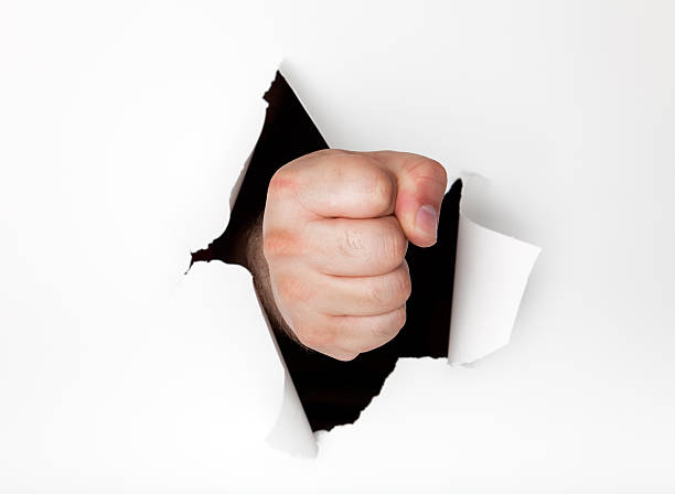 istock Man's fist punching hole through white paper (XL) 118266675