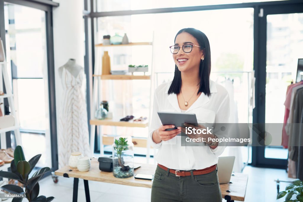 My latest post will have people running to my store Cropped shot of a young business owner using her tablet while standing in her store Owner Stock Photo
