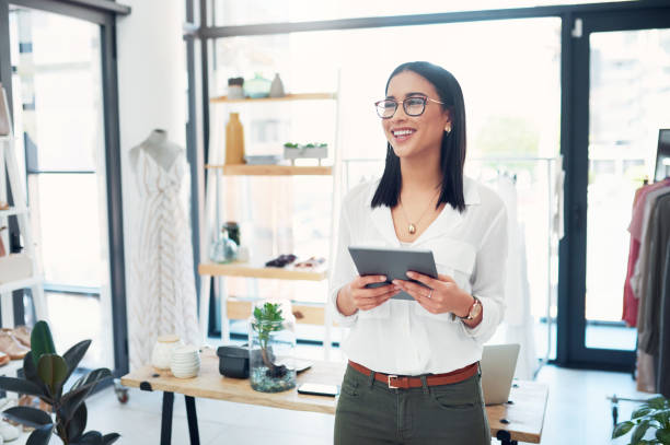 My latest post will have people running to my store Cropped shot of a young business owner using her tablet while standing in her store owner stock pictures, royalty-free photos & images