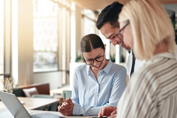 istock Smiling group of businesspeople using a cellphone in an office 1182668791