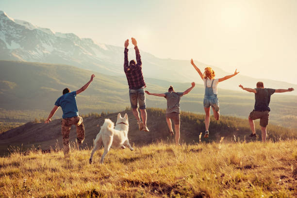 Group of friends runs and jumps in mountains stock photo