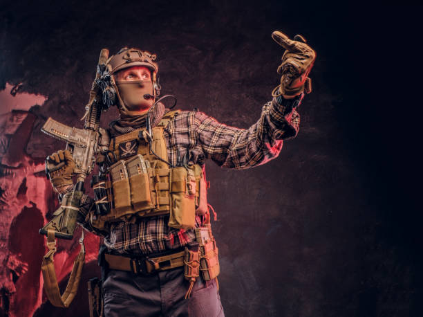 istock Special forces soldier in camouflage uniform posing with assault rifle, looks sideways and shows the middle finger. 1182674063