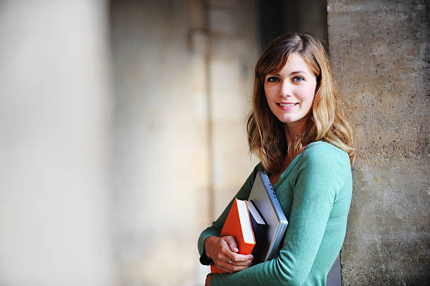 Female student holding books and a laptop stock photo