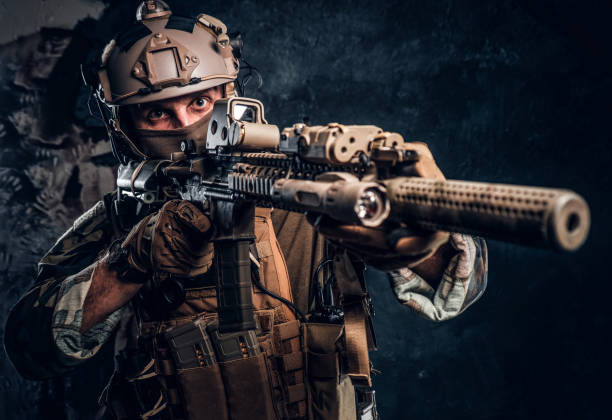 istock Elite unit, special forces soldier in camouflage uniform holding an assault rifle with a laser sight and aims at the target. 1182675678