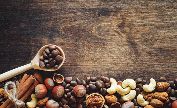 istock Different nuts on a wooden table. Cedar, cashew, hazelnut, walnuts and a spoon on the table. Many nuts are inshell and chistchenyh on a wooden background. 1182676688