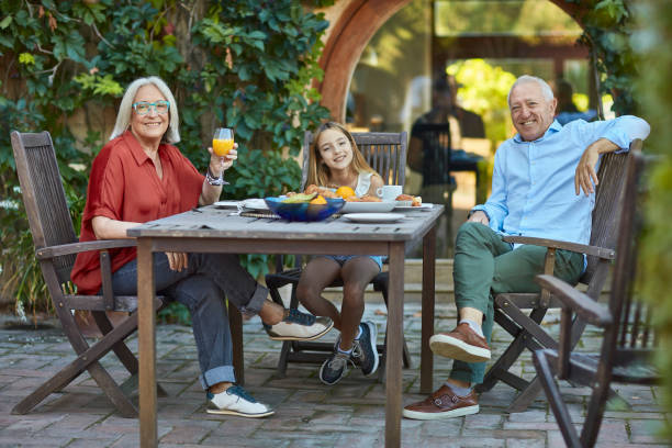 istock Relaxed Senior Couple Having Breakfast with Granddaughter 1182677092