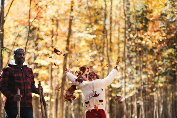 Mixed race family in a forest, throwing maple leaf, during autumn, Quebec, Canada