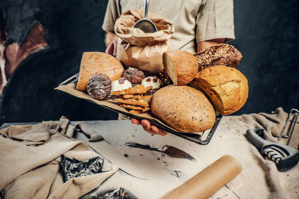 istock A baker wearing a uniform holding tray with freshly prepared products from his bakery 1182680600
