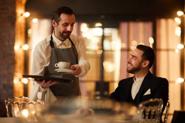 istock Smiling Waiter Bringing Coffee to Guest in Restaurant 1182684611