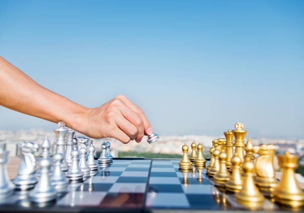 The chess player moving the pawn on the board.