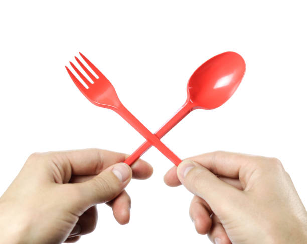 istock Hands holding plastic red disposable spoon and fork crossed. Close up. Isolated on white background 1182687508