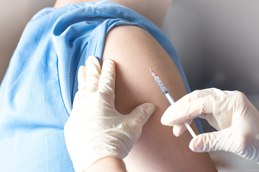 Concepto de vacunación sanitaria. Manos de médico o enfermero en guantes médicos inyectando una inyección de vacuna a un paciente hombre. photo