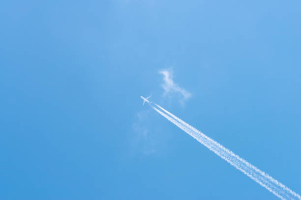 istock Airplane in a blue sky with clouds and condensation trails, Germany 1182687681