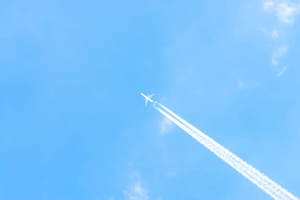 istock Airplane in a blue sky with clouds and condensation trails, Germany 1182687711