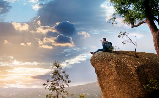 istock Hiking man sitting on the rock drinking water 1182687768