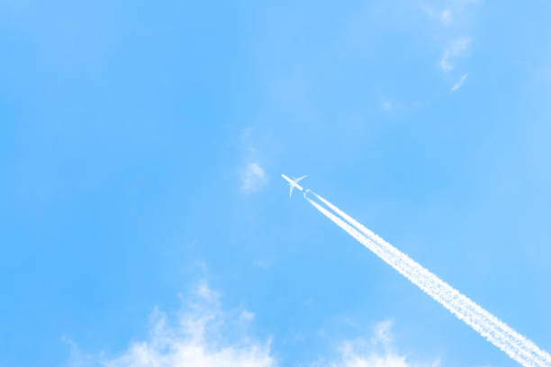 istock Airplane in a blue sky with clouds and condensation trails, Germany 1182687795