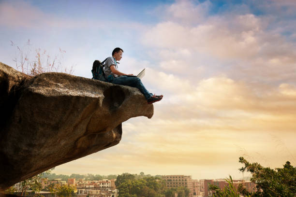 istock Man standing at the edge of a cliff using laptop 1182687826