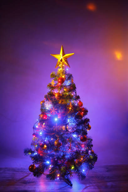 istock Christmas tree with festive lights, purple background 1182687846