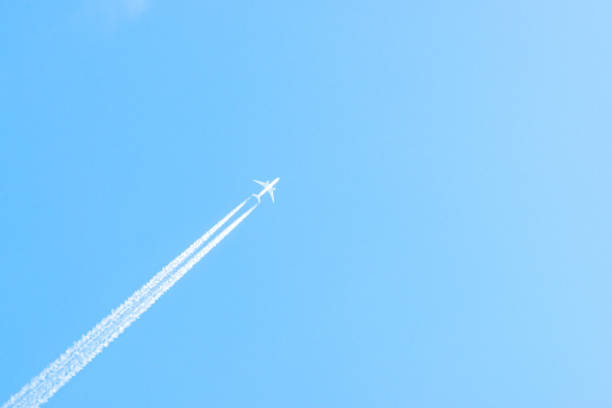 istock Airplane in a blue sky with clouds and condensation trails, Germany 1182688468