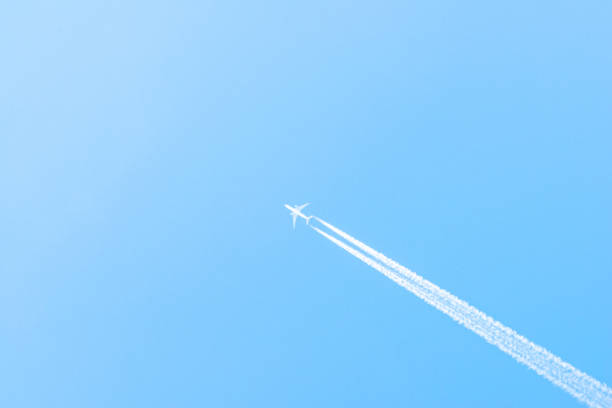 istock Airplane in a blue sky with clouds and condensation trails, Germany 1182688471