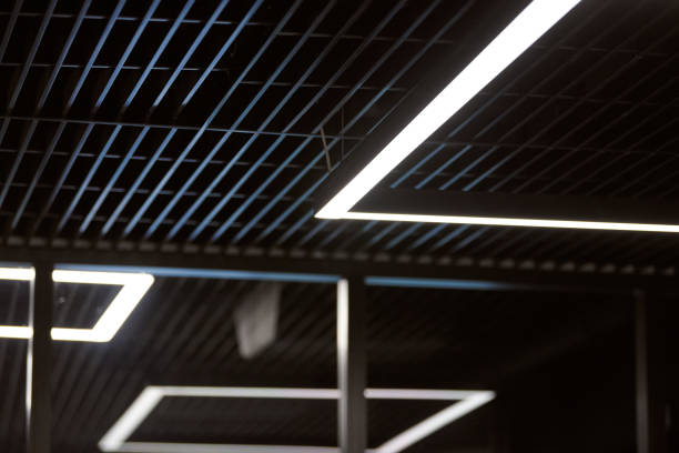 istock Modern office lighting. Thin lamps in office dark ceiling. LED white cold light over workplaces. 1182688498