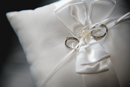 Two platinum wedding rings on a ceremonial cushion